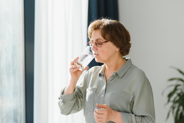 Donna anziana con bicchiere d'acqua concetto di pensione