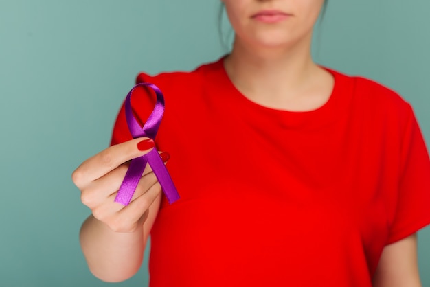 Donna anziana che tiene nastro viola. il simbolo è utilizzato per aumentare la consapevolezza per la malattia di alzheimer, l'abuso sugli anziani, l'epilessia, il cancro del pancreas, il cancro della tiroide e il lupus. avvicinamento.