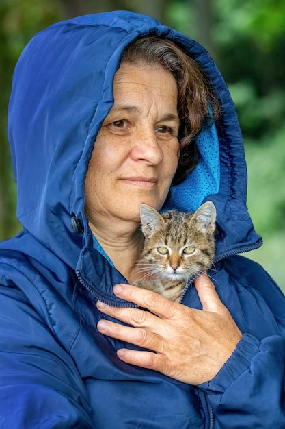 Elderly woman holding a small striped kitten, a kitten in the arms of a woman