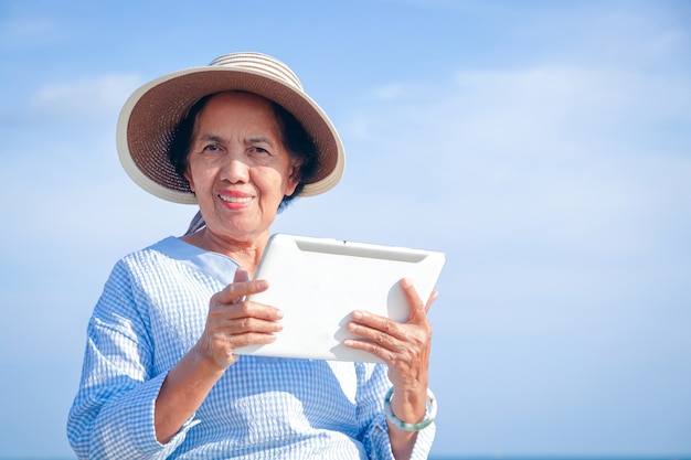 Donna anziana che tiene un tablet effettua una videochiamata online su internet per parlare con tuo figlio. concetto di pensionamento felice