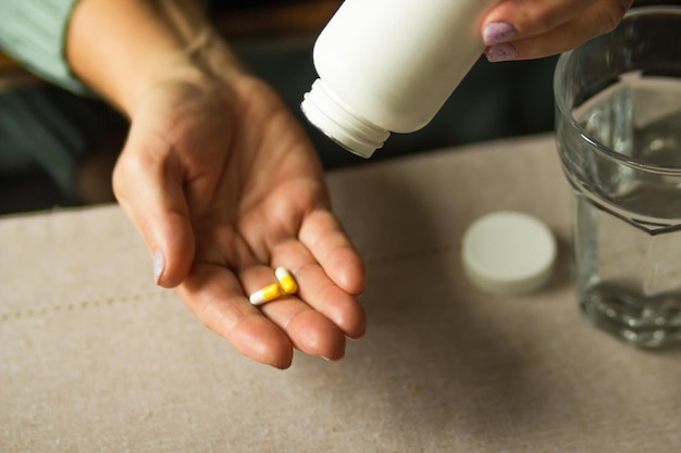 Photo elderly woman holding white plastic bottle and two capsules in hand ready to take supplement pills