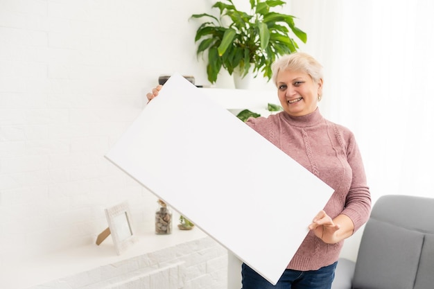 elderly woman holds a photo canvas.