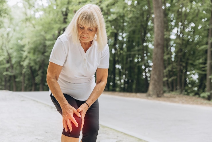 Photo an elderly woman injured her leg while running and walking standing in the park holding his knee feeling severe pain closeup photo