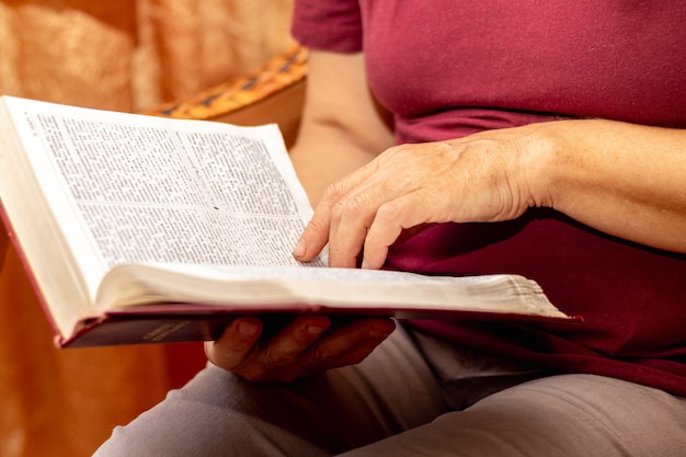 Foto una donna anziana sta leggendo la bibbia. bibbia nelle mani di una donna anziana