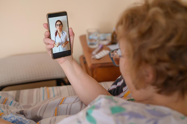 Пожилая женщина больна коронавирусом Женщина с вирусным респираторным заболеванием находится на карантине и консультируется с врачом онлайн