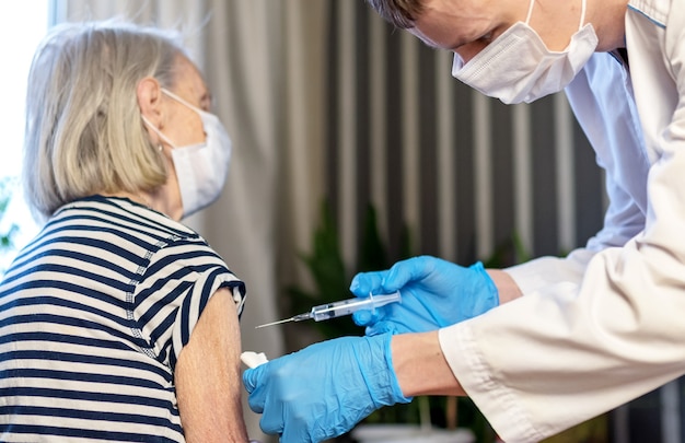 An elderly woman is vaccinated against COVID-19 in a nursing home.