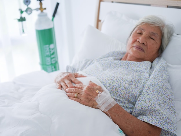 Elderly woman laying in hospital bed.