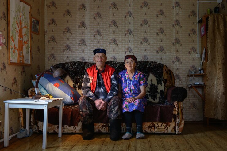 Photo elderly woman and man sitting on a sofa  in room in village house