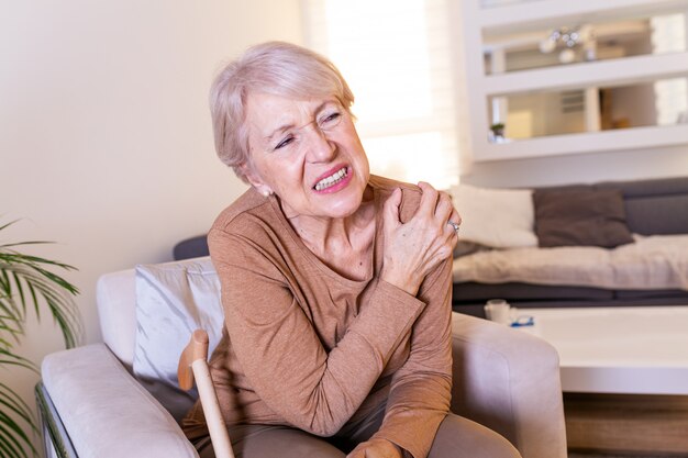 Elderly woman massaging the shoulder easing the aches.