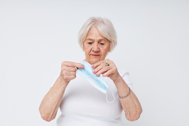 Elderly woman medical mask in hand safety light background