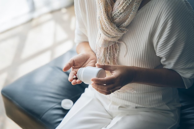 Elderly woman pouring capsule from pill bottle taking antidepressant medication senior citizen medicine medical treatment plan concept