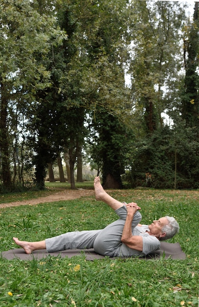пожилая женщина практикует йогу на открытом воздухе