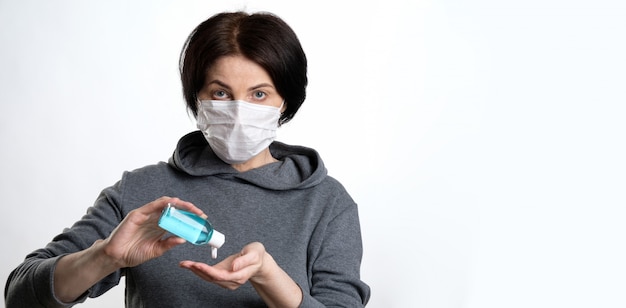 An elderly woman in a protective mask holds an antibacterial gel in her