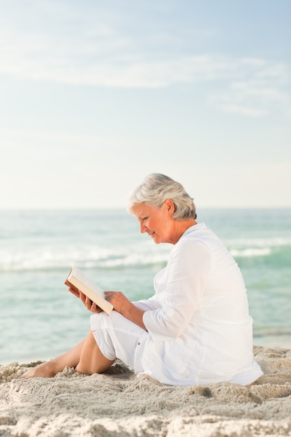 Elderly woman reading her book on the beach