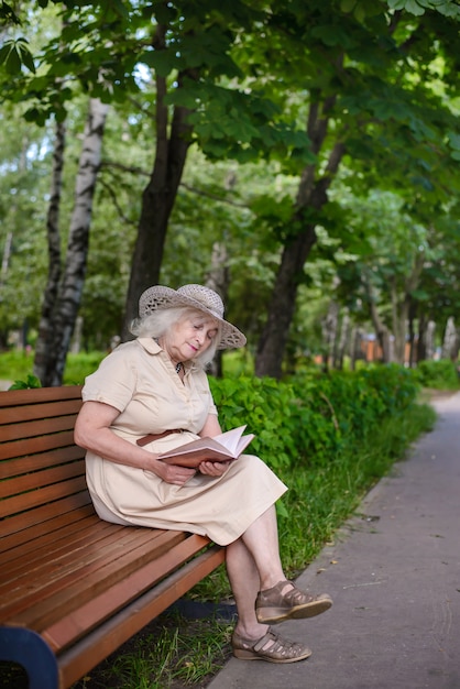 Пожилая женщина читает книгу в парке