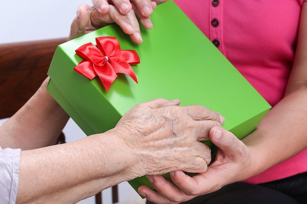 Photo elderly woman receiving a gift from daughter