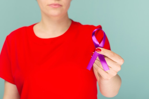 Elderly woman in red dress holding purple ribbon. Symbol is used to raise awareness for Alzheimer's disease