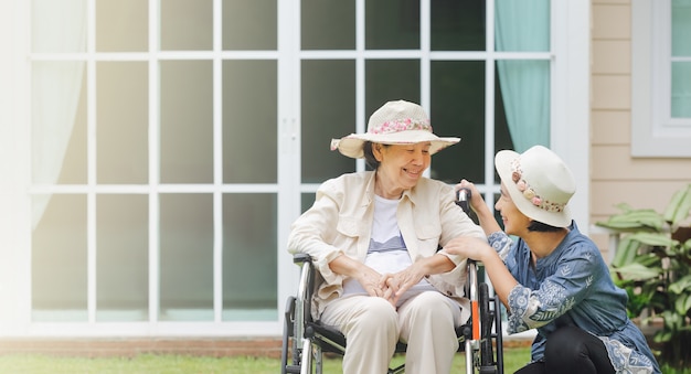 写真 高齢者の女性は娘と裏庭で車椅子でリラックスします。