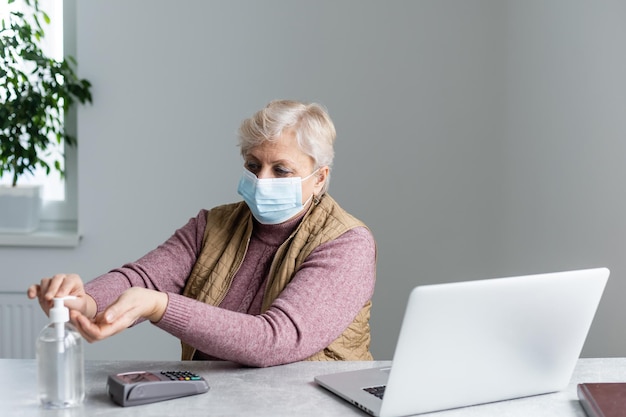 Elderly woman sanitizing her hands with alcohol gel.