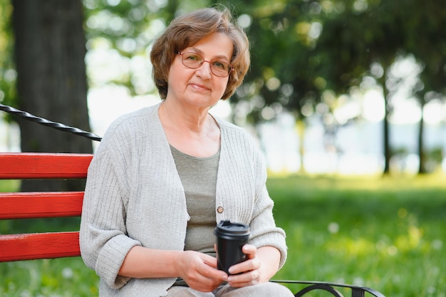 An elderly woman sitting on bench in summer park