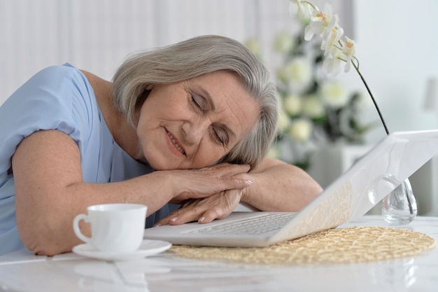 Elderly woman sleeping near  laptop at home