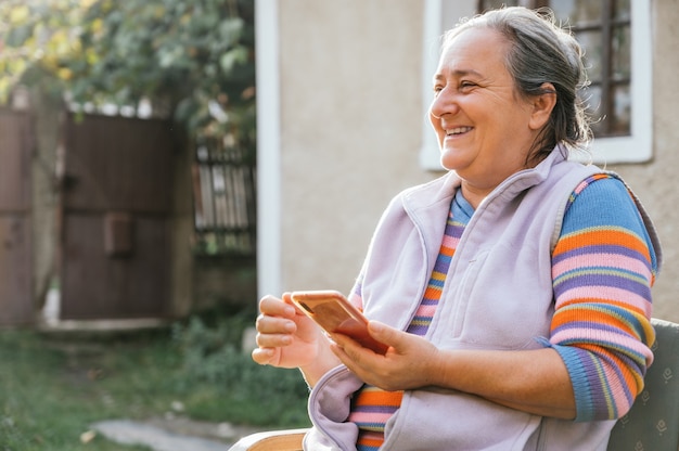 写真 笑顔でスマートフォンを使用している年配の女性