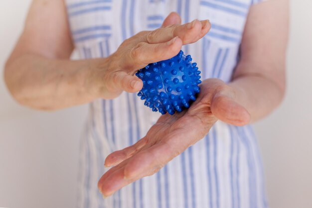 Elderly woman squeezes a prickly ball in her hands selfmassage with parkinson