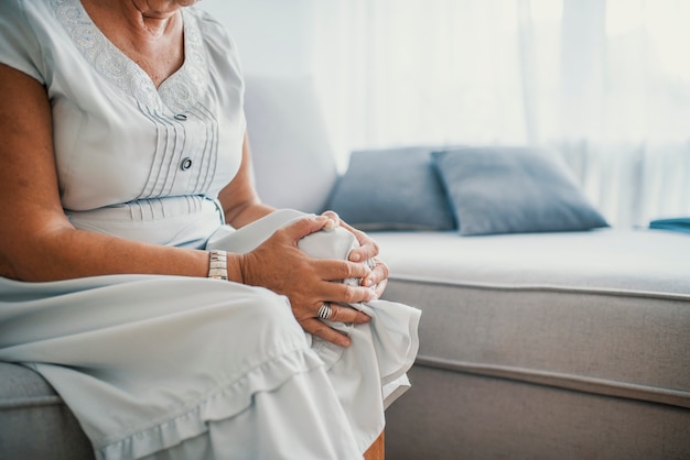 Donna anziana che soffre dal dolore al ginocchio a casa