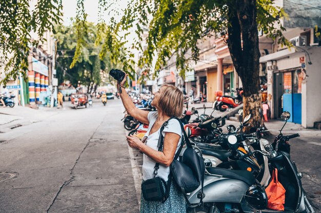 Elderly woman taking photos at the street