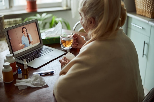 Photo elderly woman talking with doctor though video call