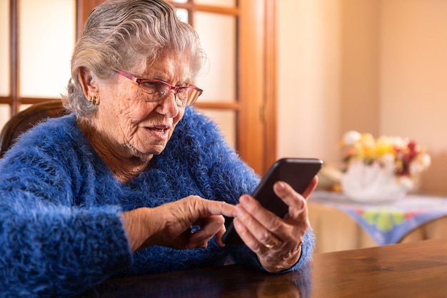 Elderly woman using a mobile phone over wood table at living room of home