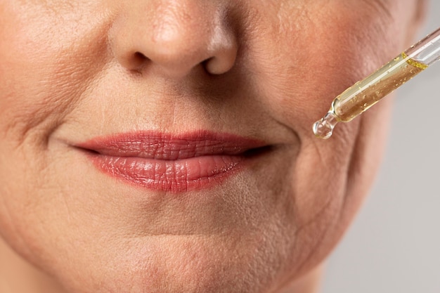 Elderly woman using serum for her mouth wrinkles