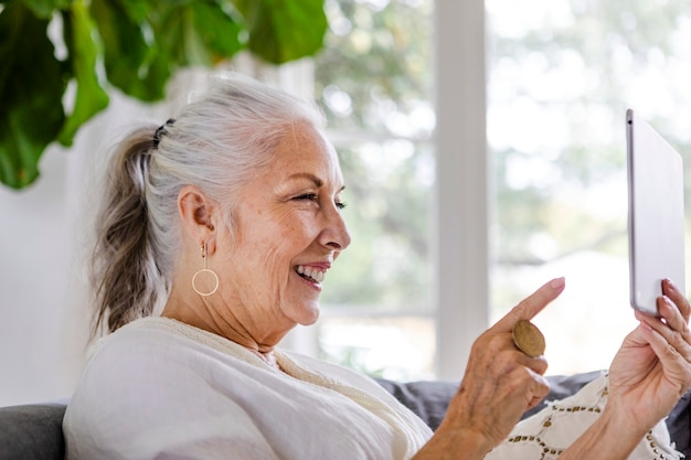 Elderly woman using a tablet on a couch