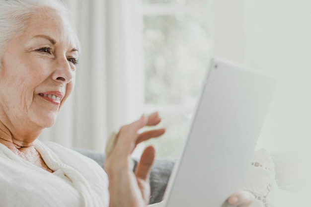 ソファでタブレットを使用している年配の女性