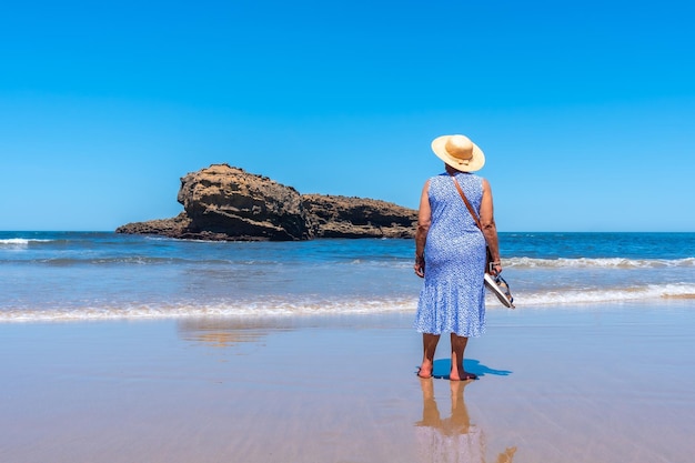 An elderly woman on vacation looking at the sea on the beach in Biarritz Lapurdi France South West resort town