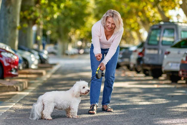 屋外で犬を連れて歩く年配の女性。