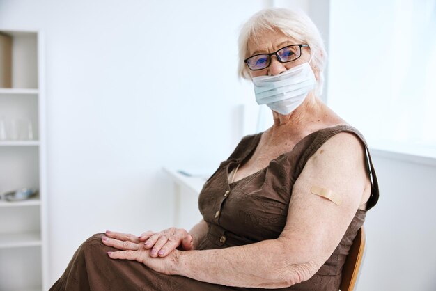 Photo elderly woman wearing glasses with plaster on her hand covid passport hospital high quality photo