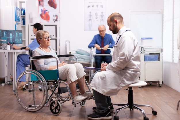 Elderly woman in wheelchair at doctor appointment in recovery clinic