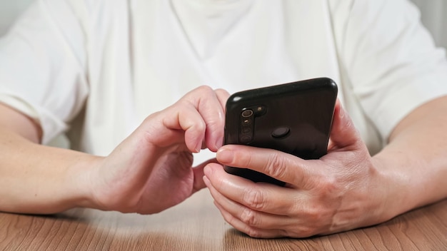 Elderly woman in white shirt learns to use modern smartphone