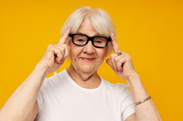 Elderly woman in a white tshirt wears glasses isolated background