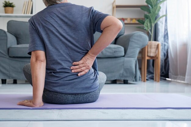 Elderly woman with back pain holding her lower back