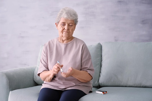 elderly woman with diabetes measuring level of blood sugar at home