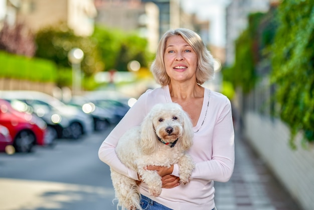 Elderly woman with a dog in her arms on a city street