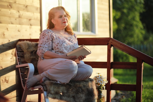Una donna anziana con un trucco da sera sotto il portico di una casa di campagna