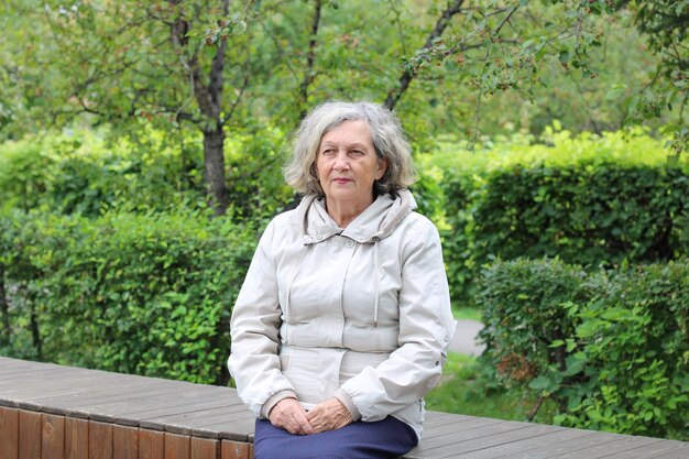 An elderly woman with gray hair is warmly dressed in cool weather Retirement age