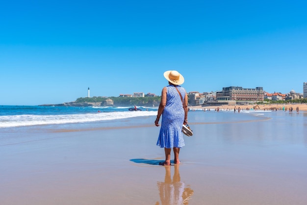 Una donna anziana con un cappello che cammina sulla spiaggia a biarritz lapurdi francia sud-ovest della località turistica