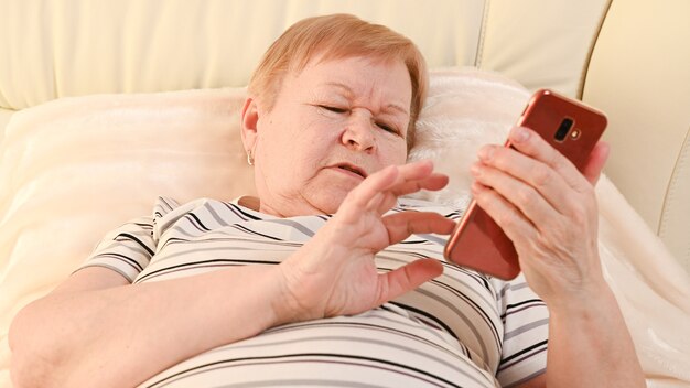 Elderly woman with mobile phone at home.