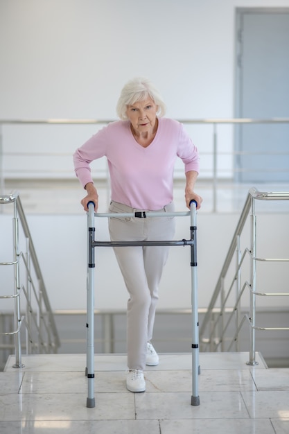 Elderly woman with a rolling-walker on the stairs