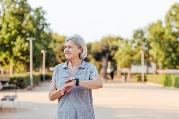 Elderly woman with a sports watch looks to the side in a park