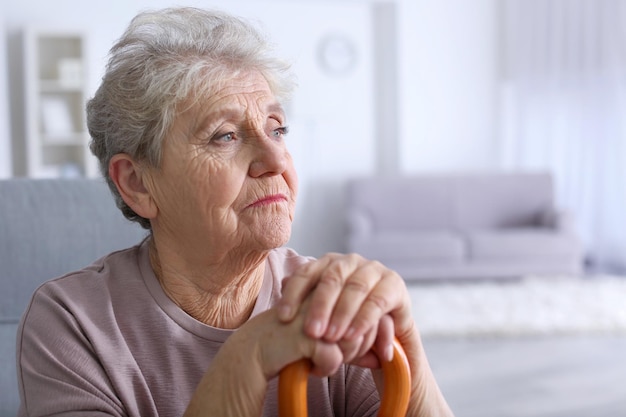 Elderly woman with walking stick at home